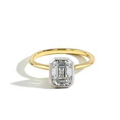 an emerald - cut diamond ring in yellow gold, set on a plain white background