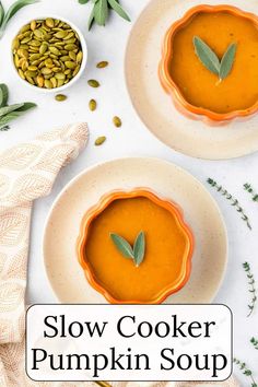 two bowls filled with pumpkin soup on top of a white table