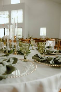 the table is set with green and white plates, silverware, and candlesticks