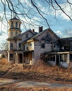 an old abandoned house sitting in the middle of a field with no leaves on it