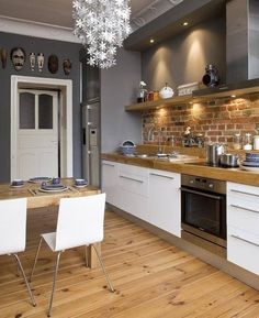 a kitchen with wooden floors and white cabinets is pictured in this image, there are many dishes on the counter