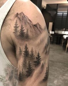 a man's upper half sleeve with trees and mountains on the back of his arm