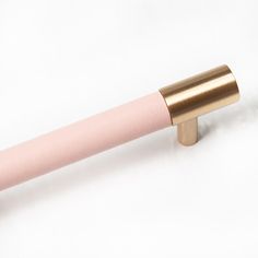 a close up of a pink and gold colored handle on a white surface with no background