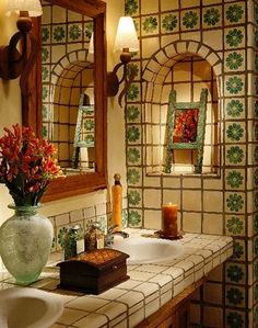 a bathroom with two sinks and a large mirror in it's center, along with a vase filled with flowers on the counter