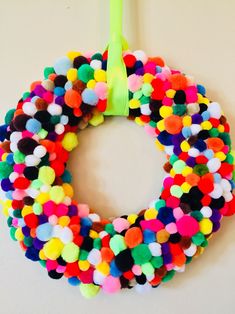 a wreath made out of pom - poms hanging on a wall