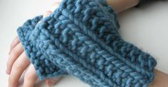 a person's hand wearing a blue knitted arm warmer on top of a white table