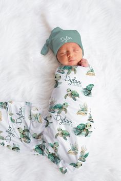 a baby sleeping on top of a white blanket wearing a green beanie and matching diaper