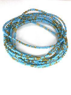 Beaded waist beads in a soft powder blue and sparkling gold! Gorgeous on any skin tone! These waist beads have metallic clasps.Waist beads, Belly Jewelry, African waist beads, Belly Chain, Belly Beads - Sparkling Powder Blue Waist Beads**** PROPERLY MEASURE YOUR WAIST ****Place the measuring tape at the exact area you prefer to wear the waist beads.Do not tuck in your stomach when measuring for belly chain.Allow for wiggle space when measuring for breathing room.Thank you for shopping with us! Blue Waist Beads With Spacer Beads As Gift, Blue Colorful Waist Beads As Gift, Adjustable Gold Beads Waist Beads For Beach, Adjustable Gold Waist Beads For Beach, Beach Gold Waist Beads With Colorful Beads, Gold Waist Beads With Colorful Beads For Beach, Blue Beaded Waist Beads As Gift, Festival Waist Chain With Gold Beads, Beaded Waist Chain For Beach With Round Beads