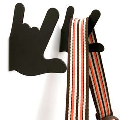 a pair of suspenders hanging on a wall with a hand sign attached to it