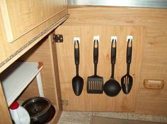 kitchen utensils are hanging on the wall in a cupboard with wooden handles and drawers