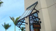 the outside of a restaurant with palm trees and blue sky in the backround