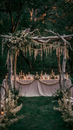 an outdoor table set up with candles, flowers and greenery for a wedding reception