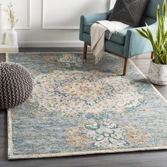 a living room area with a blue chair and large rug on the floor next to a potted plant