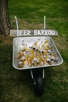 a wheelbarrow filled with beer bottles sitting on top of a grass covered field