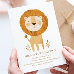 a person holding up a card with a lion on it's front and the words, mia is turning two