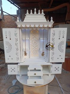 an ornate white cabinet with gold accents on the doors and drawers is being worked on