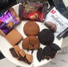 a white plate topped with lots of different types of cookies and chocolates next to each other