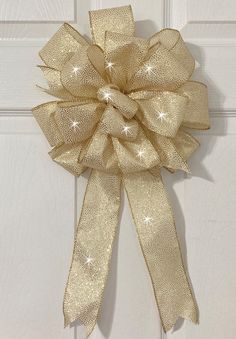 a large gold bow hanging on the side of a white door with stars and sparkles