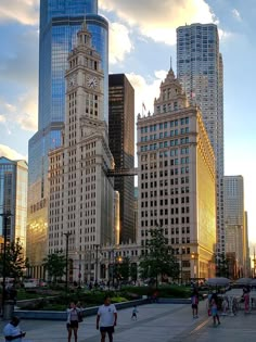 people are walking around in the city with tall buildings behind them and a clock tower