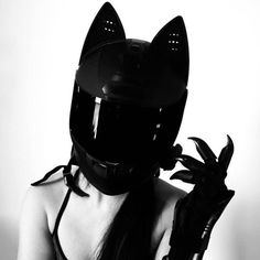 a woman wearing a black cat mask and holding a pair of gloves in her hand