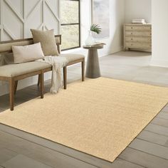 a living room with white walls and wood flooring on the floor, along with a beige area rug