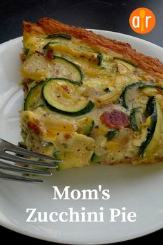 a slice of quiche with zucchini and cheese on a white plate next to a fork