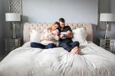 a man and woman sitting on top of a bed holding a baby in their arms