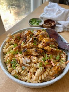 a bowl filled with pasta and chicken on top of a wooden table