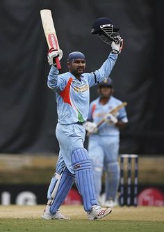 a man holding a cricket bat on top of a field