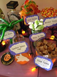 a table with candy, candies and halloween signs on it for guests to eat