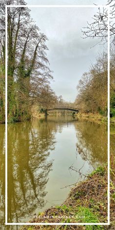 a river with trees and a bridge in the background that is framed by a white rectangle