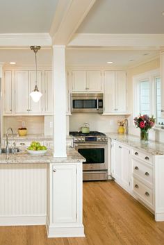 a large kitchen with white cabinets and wood flooring, along with stainless steel appliances