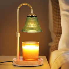 a table lamp sitting on top of a wooden stand next to a glass candle holder