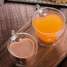 two glasses filled with liquid sitting on top of a wooden table