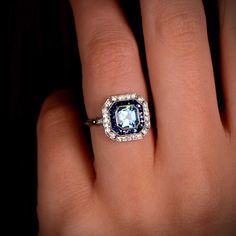 a woman's hand with a blue and white diamond ring on her left hand