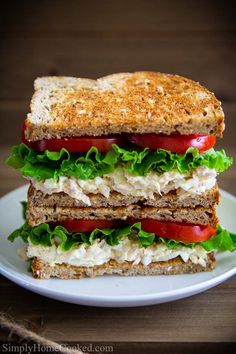 a sandwich with lettuce, tomato and cheese on it sitting on a white plate