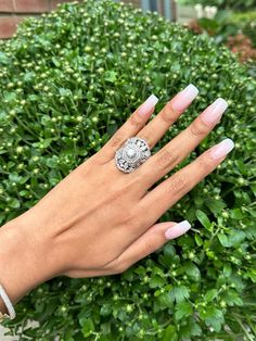 a woman's hand with white manicured nails and a ring on her finger