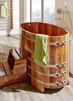 a wooden bucket with towels in it next to a window and towel rack on the floor