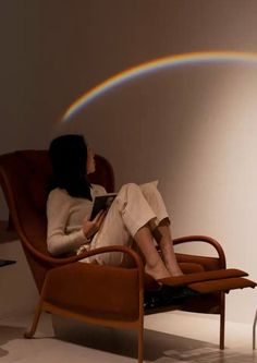 a woman sitting in a chair with a rainbow behind her