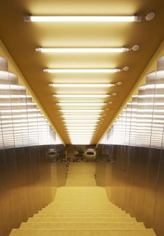 an empty hallway with stairs leading up to the ceiling and lights on either side of it