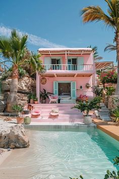 a pink house with palm trees in front of it and a pool next to it