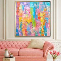 a living room with a pink couch and painting on the wall above it's coffee table