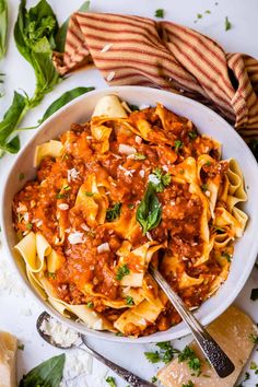 a white bowl filled with pasta and sauce on top of a table next to bread