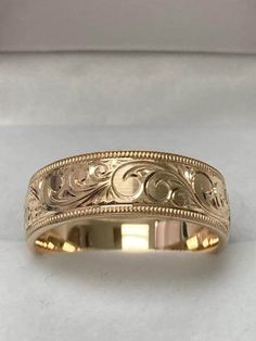 a gold wedding band with intricate designs on it