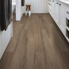 a kitchen with white cabinets and wood flooring on the walls, along with a wooden stool