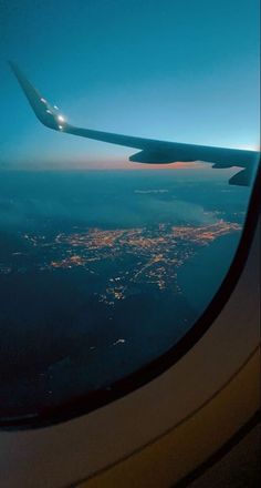 the wing of an airplane as it flies above the city lights at night from below