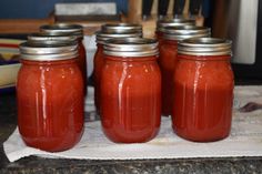 four jars filled with red liquid sitting on top of a counter