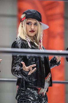 a woman in black jacket and hat standing on top of a metal rail with her hands out