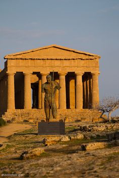 an ancient greek temple with a statue in the foreground and trees on the other side