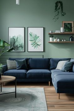 a living room with green walls and blue couches in the corner, two paintings on the wall